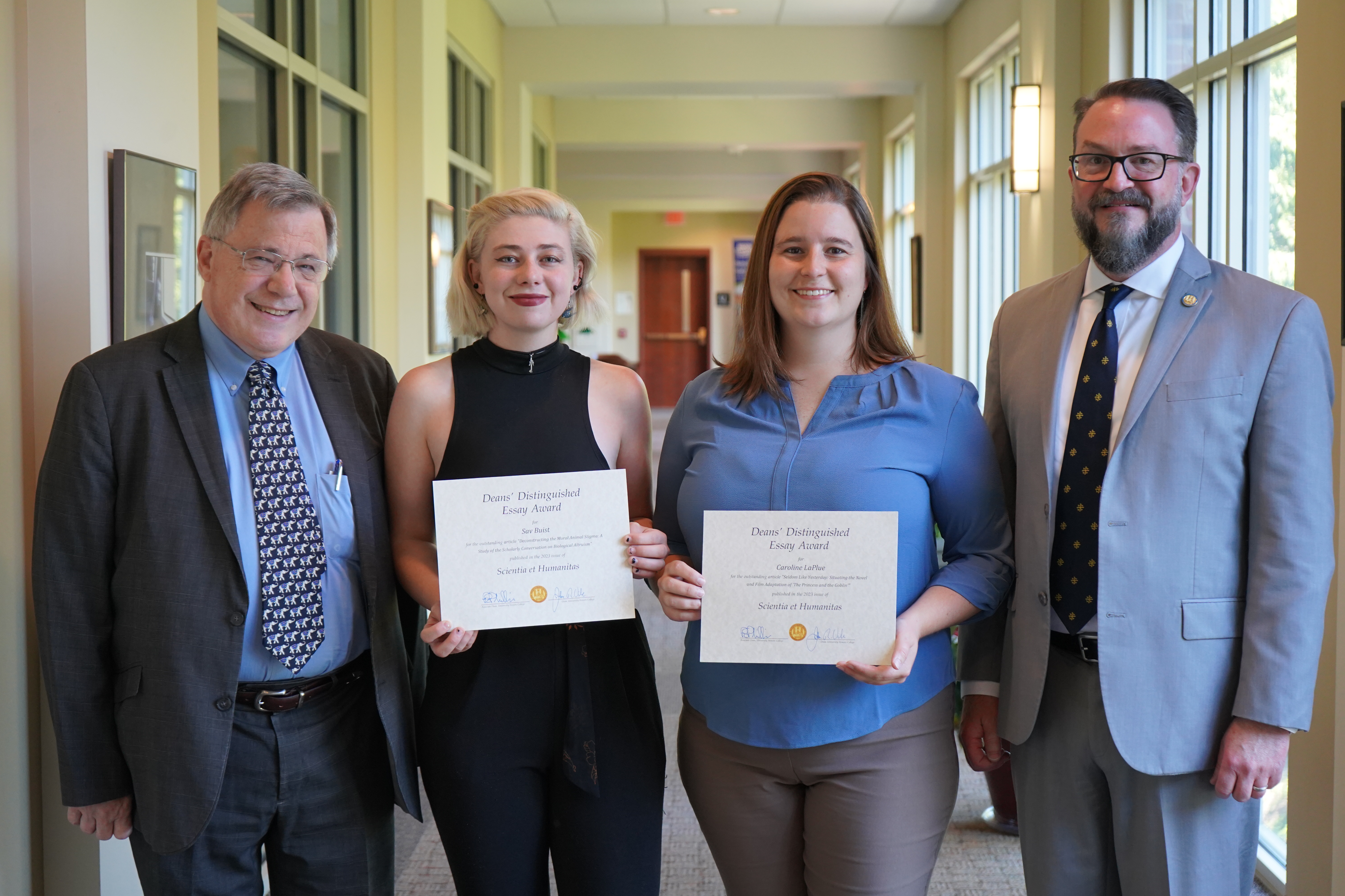 Photo of, from left to right, Dean Vile, Sav Buist, Caroline LaPlue, and Dean Phillips. Buist and LaPlue are holding ceritificates recognizing their Deans Distinguished Essay.
